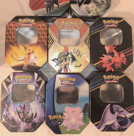 Assortment of official large Pokémon tins featuring Pikachu, Zapdos, Moltres, Mewtwo, Clefairy and more
