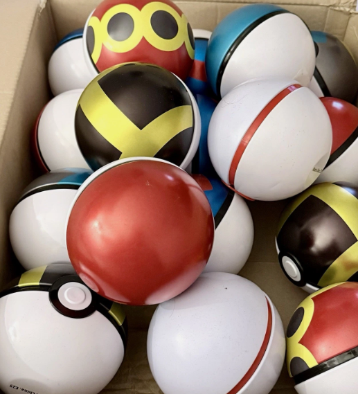 Box of assorted Pokéball shaped tins including Pokéball, Great Ball, Ultra Ball, Quick Ball and more